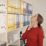 Medicine Cabinet - Pensive female worker choosing folder with documents in modern office